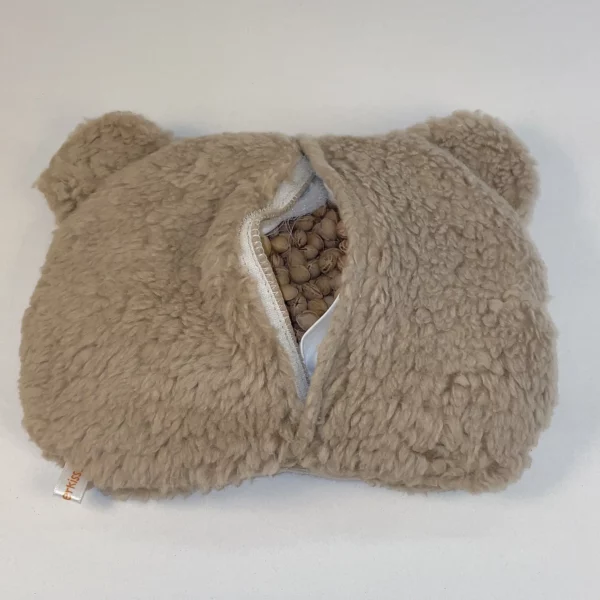 Kirschkernkissen Bär in Farbe braun. Zu sehen ist die Rückseite. Der Klettverschluss vom Überzug und vom Innenkissen ist geöffnet und die Kirschkerne sind zu sehen. Kirschkernkissen speichern die Wärme bist zu 25 Minuten. Das Wärmekissen Bär kann mit Überzug in der Mikrowelle aufgewärmt werden.