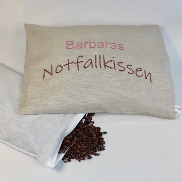Traubenkernkissen Geschenk für Frauen mit Personalisierung. Auf das cremefärbige Traubenkernkissen wurde gut leserlich "Barbaras Notfallkissen" in Farben rosé und braun gestickt. Das handgemachte Wärmekissen mit Größe 20*25 cm ist waschbar. Die Kerne sind durch einen Klettverschluss im Innenkissen austauschbar.