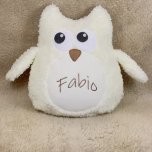 Schneeeule personalisiert, aus Baumwollplüsch mit großen Flügeln. Die Farbe des Kuscheltieres ist ein helles creme. Die Flügel stehen vom Kuscheltier ab und laden zum Greifen ein. Die Augen, der Schnabel und der Bauch sind mit Vliesstoff liebevoll dargestellt. Auf den Bauch wurde der Name Fabio in brauner Farbe eingestickt. Der Name ist etwa 4 cm hoch und 10 lang.