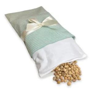 Aufwärmbares Wärmekissen mit Satinbandschleife, hergestellt aus Baumwollstoff. Der Überzug von diesem Wärmekissen ist in dezenter mint Farbe hergestellt. Das Innenkissen wurde auf dieser Abbilding ein paar Zentimeter herausgezogen und ist geöffnet. Die Kirschkerne sind sichtbar. Das Innenkissen kann herausgenommen werden und hat einen Klettverschluss. Dadurch können die Kirschkerne ausgetauscht oder vor dem Waschen rausgenommen werden. Der Überzug und das Innenkissen sind pflegeleicht und können gewaschen werden.