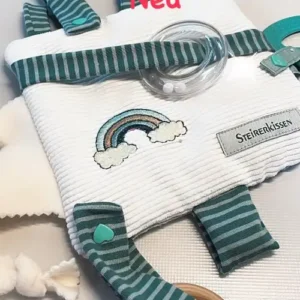 Sensorik Spielzeug für Babys. Geschenk zur Geburt und passend für Maxi Cosi. Abgebildet ist ein Quadratisches, flaches Kissen mit Überzug auf beigem Cordstoff und einem aufgestickten Regenbogen. Die Farben im Regenbogen in mint, petrol und dunkelgrün passen genau zu den angenähten Schleifen, mit denen die Rassel und die beiden Beißringe am Kissen befestigt sind.